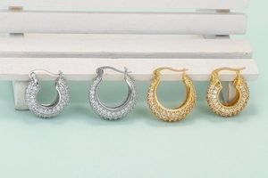 U-shaped hoop earrings with zircon pavé in gold and silver finishes on a mini bench