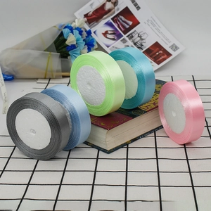 Glossy satin ribbons in blue, mint, and pink stacked neatly for gift wrapping