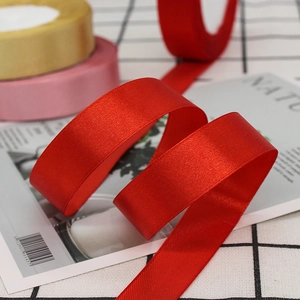Close-up of 2cm red satin ribbon with glossy texture for gift wrapping and DIY crafts