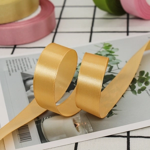 Macro shot of 2cm golden satin ribbon roll with a glossy texture for gift wrapping