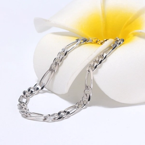Macro view of sterling silver Figaro chain bracelet with lobster clasp and floral decor