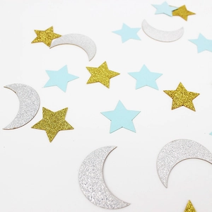 Close-up of glitter gold stars, silver moons and blue paper confetti party decorations