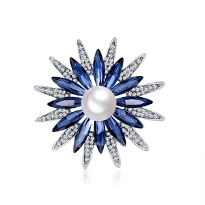 Detail view of sunflower brooch with blue crystals, white pearl, and silver metal base