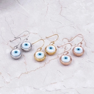 Fashionable evil eye earrings set in silver gold and rose gold on marble background
