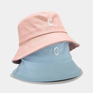 Dettaglio del ricamo della lettera C su cappelli alla pescatora in cotone azzurro e rosa