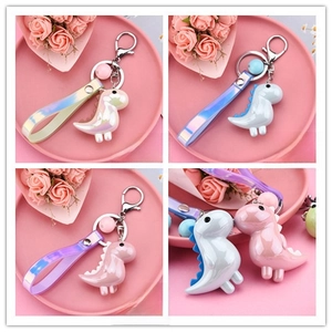 Detailed view of colorful acrylic dinosaur keychains in light yellow, blue, and pink colors