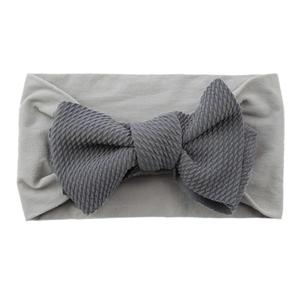 Close-up of soft grey baby headband with a dark grey knitted bow on white background