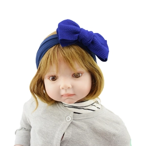 Close-up of baby girl wearing a large blue nylon bow headband on a doll model