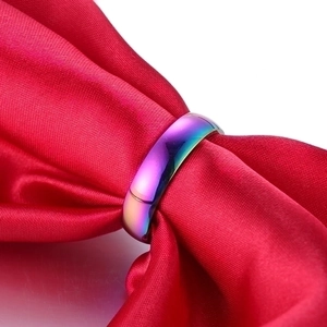Rainbow gradient stainless steel ring displayed on elegant red silk fabric background