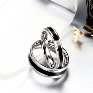 Titanium steel couple rings with black enamel inlay stripes on a reflective surface