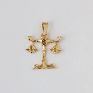 Macro shot of gold plated stainless steel Libra zodiac scales pendant with smooth finish
