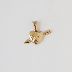 Close-up of golden heart pendant with arrow and star motif on white background