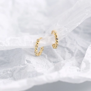 Macro detail of gold S925 sterling silver hoop earrings featuring clear zircon stones