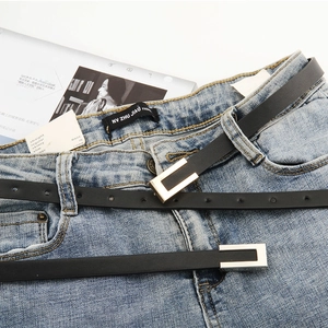 Minimalist black slim belt with gold buckle styled on blue denim jeans for casual outfits