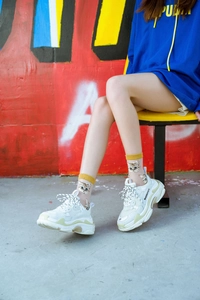 Close-up of white chunky sneakers with lime accents and cat pattern crew socks
