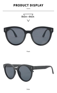 Detail view of black oversized round sunglasses with intricate embossed patterns on temples