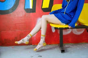 Detail of yellow cotton cuffs and toe on transparent mesh socks with cat embroidery