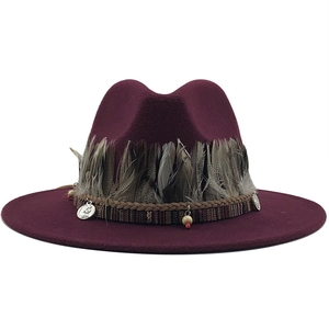 Detail of burgundy wool fedora with bohemian feather trim and ethnic beaded charms