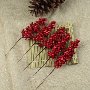 Close-up of red artificial berry stems for Christmas DIY decor on rustic burlap fabric