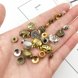 Mix of alloy elephant and Buddha spacers held in hand for jewelry making DIY