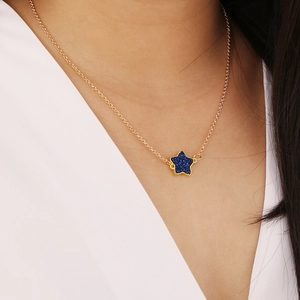 Minimalist gold necklace with a vibrant blue star pendant on a female model neck