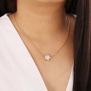 Close-up of golden necklace with a textured star pendant worn on a model's neck