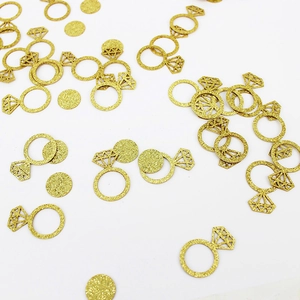 Glittery gold diamond ring and round paper confetti for wedding and party decorations