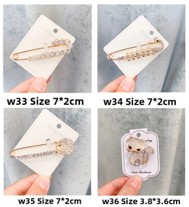 Détail de diverses broches en alliage avec strass et perles de chat présentées à la main