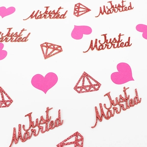 Close-up of rose gold Just Married glitter confetti with hearts and diamond shapes