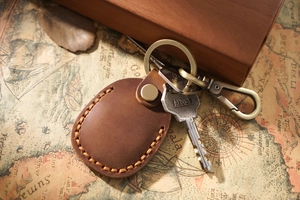 Detailed view of a brown leather AirTag keychain with brass hardware and two metal keys