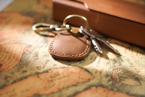 Close-up of brown leather AirTag keychain with manual stitching and brass hardware