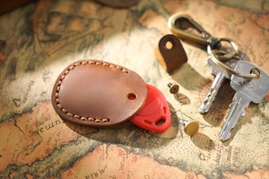 Close-up of brown leather key fob cover with red proximity tag on vintage map