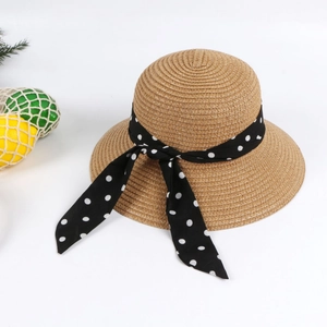 Detail of straw hat with black polka dot ribbon and bow on a vacation background