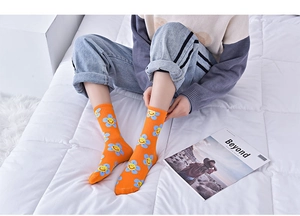 Close-up of orange cotton socks with blue flowers and yellow smiley faces on a model