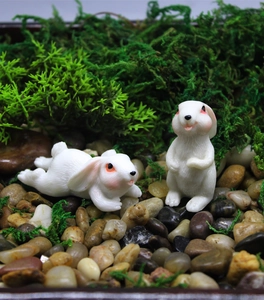 Detailed view of two cute white resin bunny figurines in a mossy micro landscape