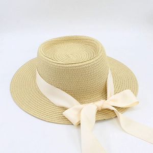 Detailed close-up of a beige flat-top straw hat with an elegant cream ribbon and bow