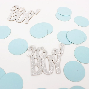 Close-up of glittery silver 'it's a BOY' text confetti and light blue round paper dots