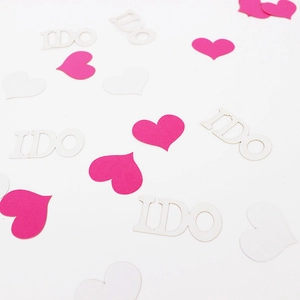 Scattered pink hearts and white I DO paper confetti decorations for wedding parties