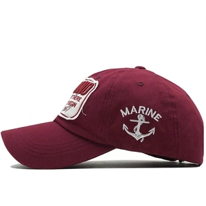 Detail of white Marine text and anchor embroidery on a burgundy cotton baseball cap