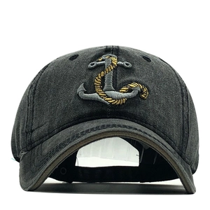 Detail of nautical anchor and rope embroidery on a washed dark gray denim baseball cap