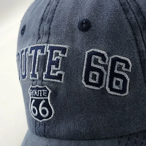 Close-up of Route 66 embroidery and shield patch on washed navy cotton baseball cap