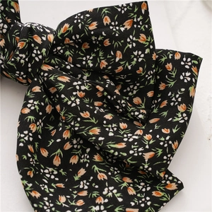 Macro detail of triple-layered floral bow hair clip with orange tulip pattern
