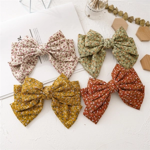 Detailed view of four large floral fabric bow hair clips in vintage rustic patterns