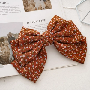 Detail of large bow hair clip with vintage red floral fabric on a lifestyle magazine