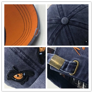 Navy washed denim baseball cap with eye embroidery and contrasting orange brim detail