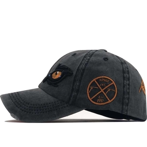 Detailed embroidery of eye motif and circular badge on charcoal cotton baseball cap