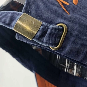 Macro detail of the vintage brass adjustable metal buckle on navy blue baseball cap