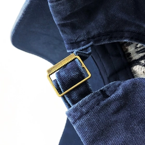 Macro detail of adjustable fabric strap and brass metal buckle on washed cotton baseball cap