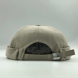 Detail of beige cotton docker cap showing adjustable back strap and silver metal buckle