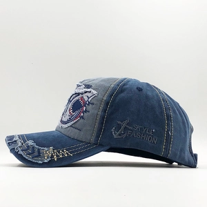Detail of distressed washed denim baseball cap with shark patch and side anchor embroidery